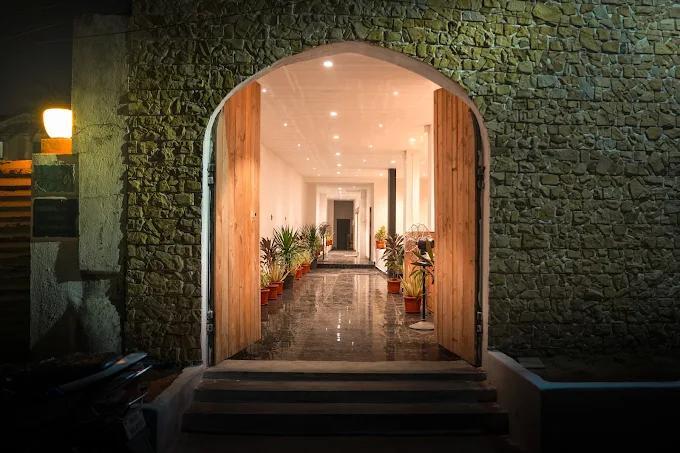 Stone archway entrance of The Tides by the Beach, lit at night